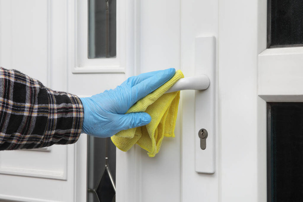 Human hand in protective gloves  cleaning house door handle using antibacterial or cleaning solution and cloth - Foto, Imagem