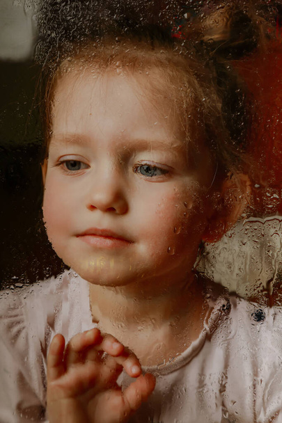 portrait of a little girl behind the surface with drops - Foto, Imagen