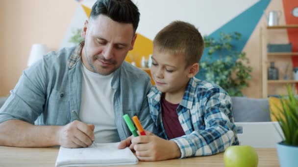 Caring father creative man drawing pictures while kid watching sitting at desk in house - Záběry, video