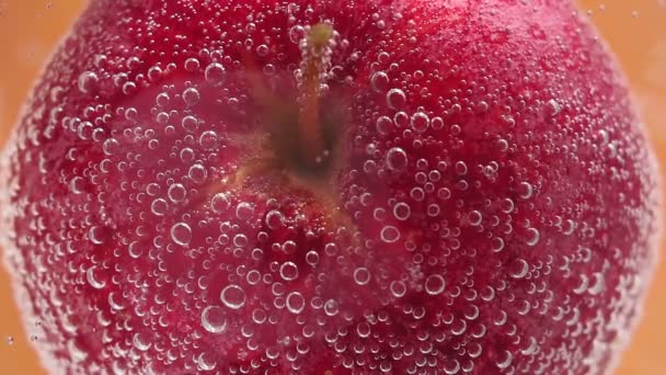 μήλο κάτω από το νερό με ένα ίχνος διαφανούς φυσαλίδας. Κοντινό πλάνο, επιλεκτική εστίαση. ζουμερά ώριμα φρούτα στο νερό - Πλάνα, βίντεο