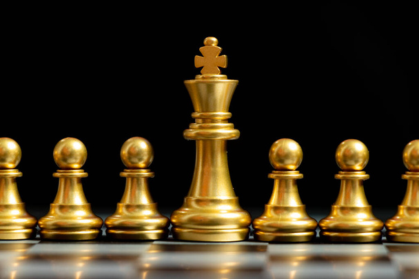Zlatý šach kus stojan s pěšcem na černém pozadí (Koncept týmové práce, management) - Fotografie, Obrázek