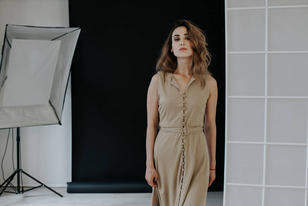 Portrait of a fashionable woman in a beige dress in a photo studio - Photo, Image