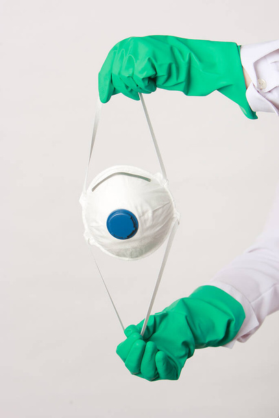 Hand in Hand mit blauen Nitrilhandschuhen und Atemschutzmaske. N95, FFP2, COVID-19, 2019-nCoV, Virenschutz, Staubmaskenkonzept. Weißer Hintergrund - Foto, Bild