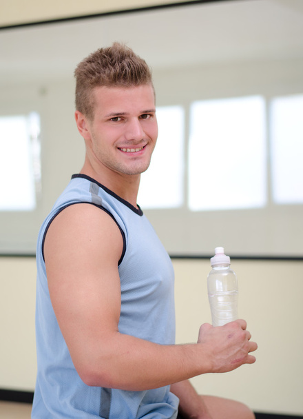 Attractive, nice male athlete holding plastic bottle of water - Photo, image