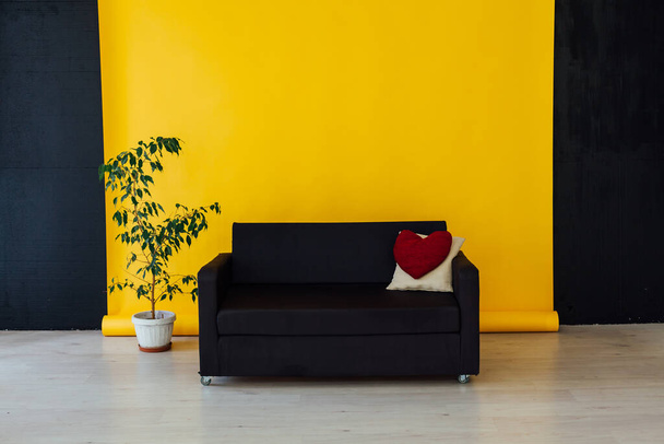 μαύρος καναπές με μαξιλάρια στο εσωτερικό του κίτρινου δωματίου - Φωτογραφία, εικόνα