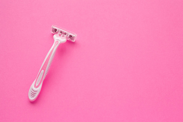 Woman pink plastic razor on pink background. Space for text. Disposable female shaver. - Fotó, kép