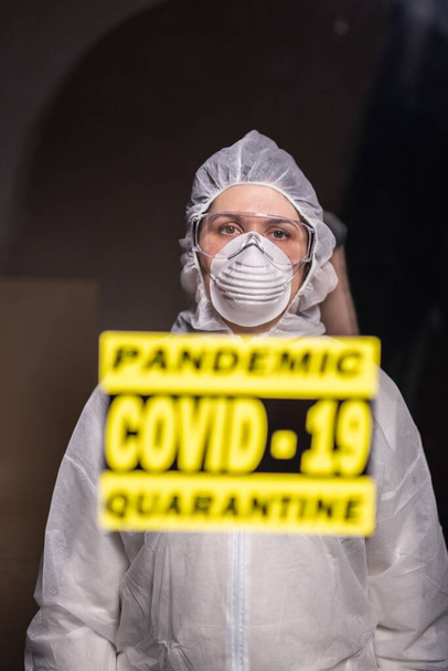 Mujer con mono blanco protector, máscara y gafas en la cara. Coronavirus, pandemia, covid-19, gripe y concepto de cuarentena
. - Foto, imagen