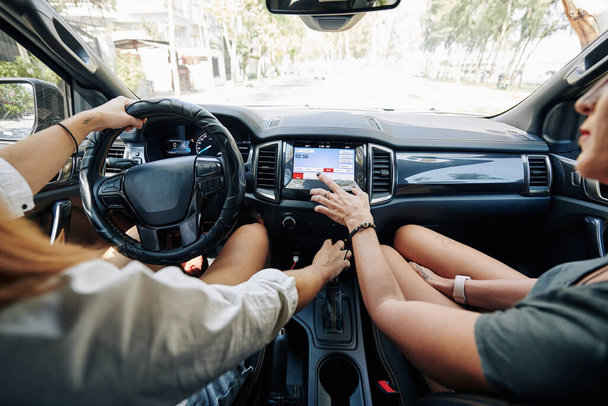Vrouwelijke vrienden kiezen radiostation met goede muziek tijdens het rijden in de auto - Foto, afbeelding
