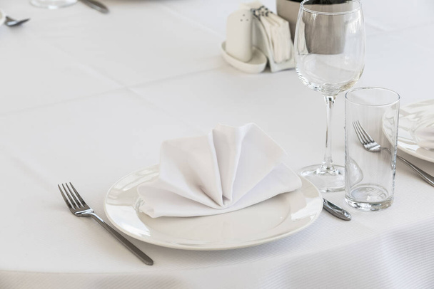 Serving a table in the restaurant waiting for guests and visitors. White tablecloth, napkins, plates and wine glasses. there is nobody - Fotoğraf, Görsel