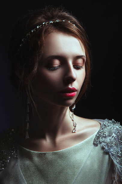 Emotional old-fashioned portrait of a girl in retro style in a light transparent dress with shiny elements on the shoulders. - Foto, Bild