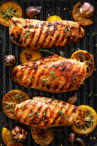 Grilled chicken breasts with thyme, garlic and lemon slices on a grill pan close up, top view - Photo, Image
