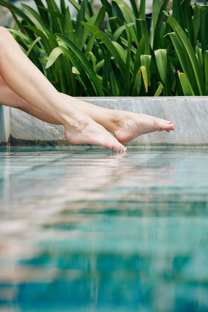 Jalat nuori nainen roiskuu vettä uima-altaassa
 - Valokuva, kuva