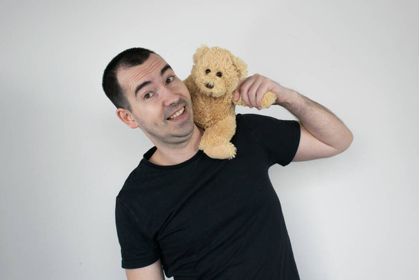 Взрослая привязанность белый фон мужчина стоять медведь крупным планом счастливая черная футболка мужчина
 - Фото, изображение