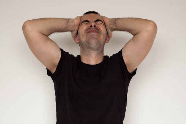 fehér férfi migrén fejfájásfekete póló közelkép kezek fehér háttér fájdalmas - Fotó, kép