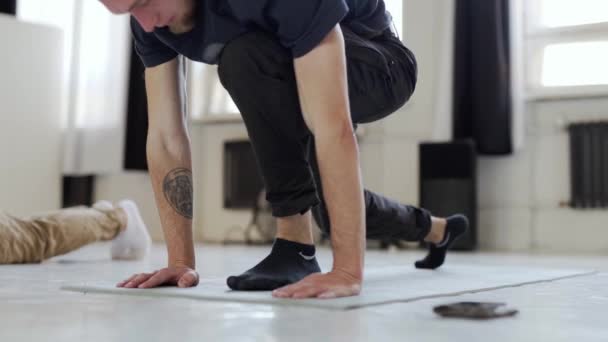 mężczyzna w czarnej odzieży sportowej ćwiczy jogę - Materiał filmowy, wideo