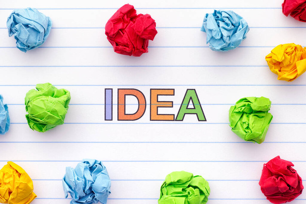 The word Idea written on a lined notebook sheet with some crumpled paper balls around it. Close up. - Foto, Imagem