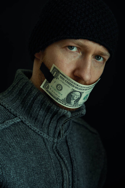 汚職や贈賄の概念イメージ。お金のために沈黙。口を閉じた男の肖像とともに1ドル紙幣.  - 写真・画像