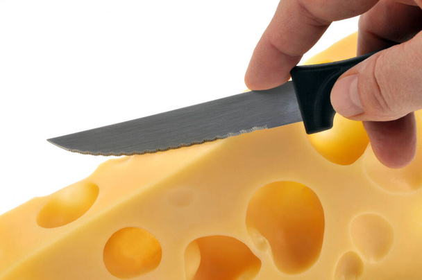 Beyaz arka planda yakın plan bir bıçakla bir parça Emmental peyniri kes.  - Fotoğraf, Görsel