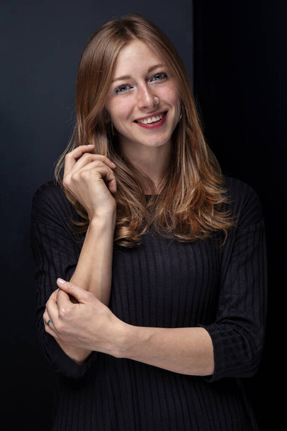 Porträt einer schönen sommersprossigen jungen Frau mit einem Nasenpiercing auf schwarzem Hintergrund - Foto, Bild
