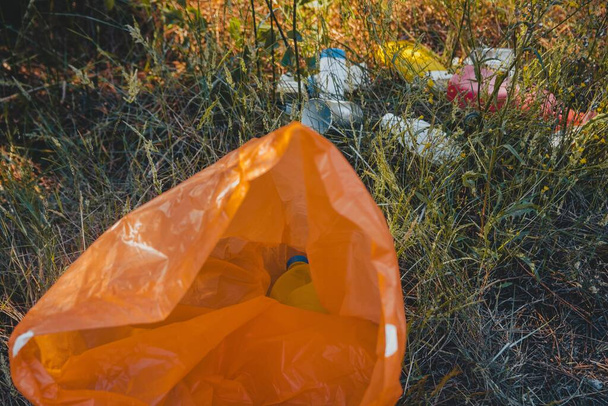 An orange plastic garbage bag on the ground - environmental pollution concept - Фото, изображение
