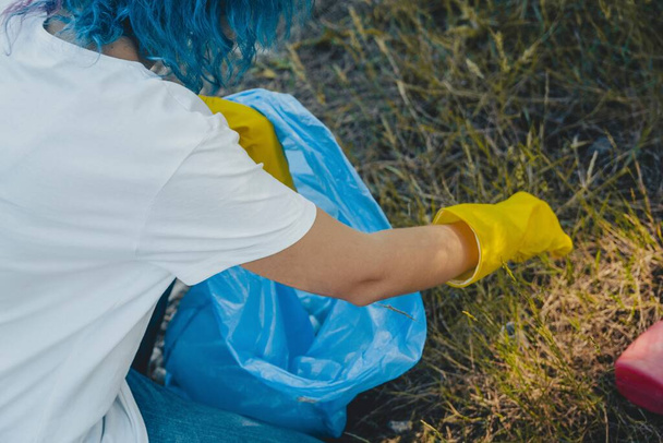 A young female collecting the trash and putting in a plastic garbage bag - environmental pollution concept - Фото, зображення