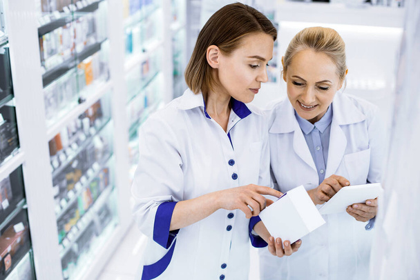 Young attentive female pharmacists checking new medication - 写真・画像