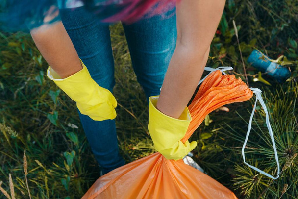 A young female collecting the trash and putting in a plastic garbage bag - environmental pollution concept - Foto, immagini