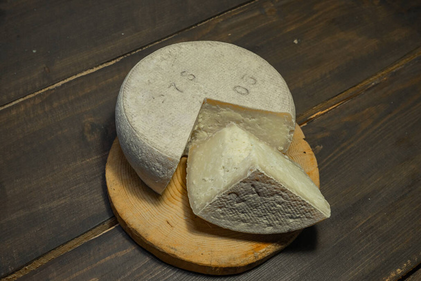 Arrangement with appetizing cheese on the kitchen cutting board. - Fotó, kép