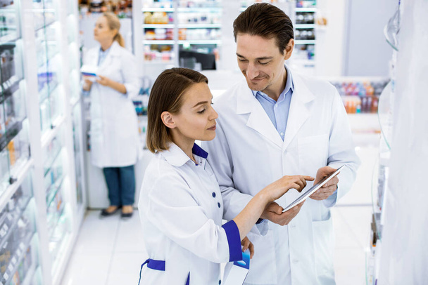 Two pharmacists checking the availability of medicines in a pharmacy. - Фото, изображение