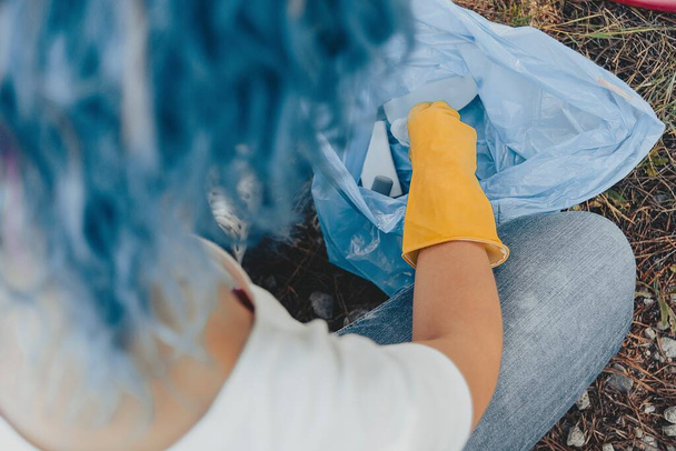 A young female collecting the trash and putting in a plastic garbage bag - environmental pollution concept - Valokuva, kuva
