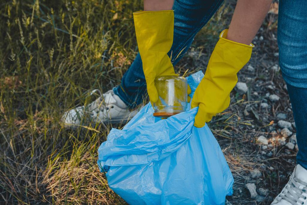 A young female collecting the trash and putting in a plastic garbage bag - environmental pollution concept - Fotoğraf, Görsel