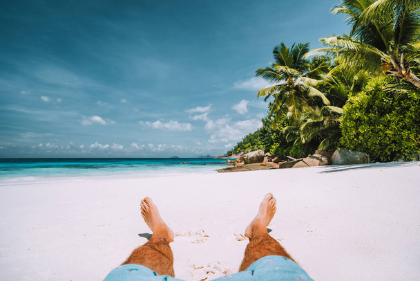muž odpočívající na bílé písečné pláži s krásnými palmami - Fotografie, Obrázek