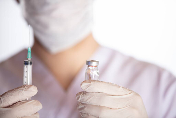 A health worker holding syringe and vial with vaccine against COVID-19, measles and flu - Foto, afbeelding