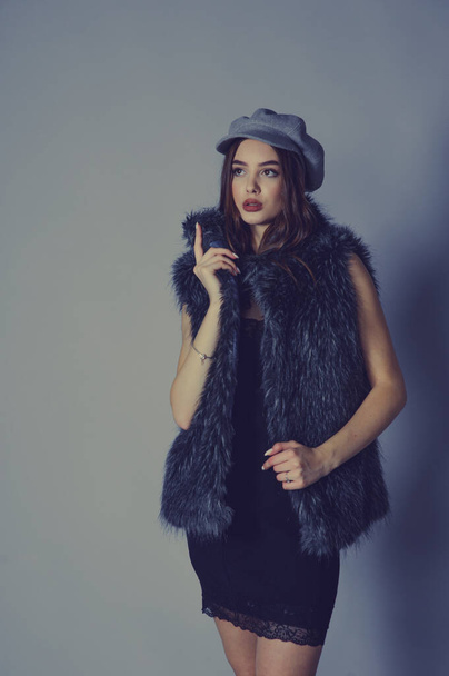 Portrait. magnificent portrait of a beautiful young woman. Perfect face beautiful girl portrait. brunette girl. Girl in a gray hat. little black dress. Girl in a vest with faux fur. Girl in a studio - Foto, Imagem