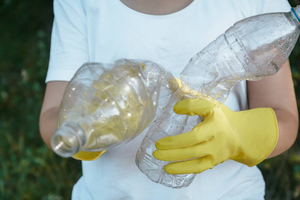 Самка с голубыми и розовыми волосами в перчатках с пластиковыми бутылками для вторичной переработки - концепция загрязнения пластика - Фото, изображение