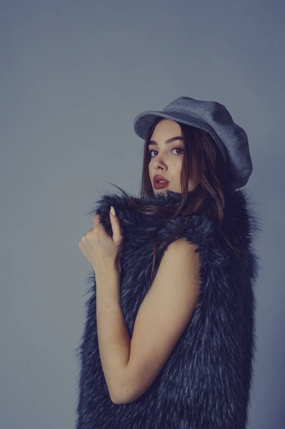 Portrait. magnificent portrait of a beautiful young woman. Perfect face beautiful girl portrait. brunette girl. Girl in a gray hat. little black dress. Girl in a vest with faux fur. Girl in a studio - Foto, afbeelding