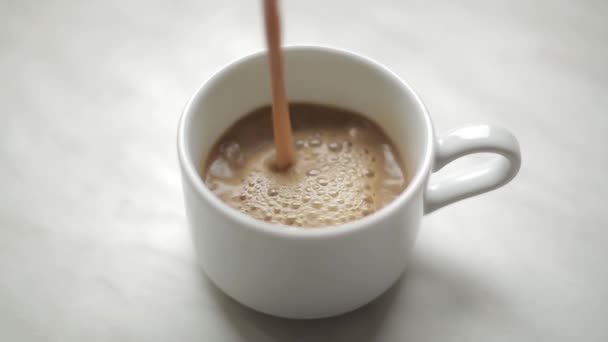 Coffee with milk is poured into a mug - Materiał filmowy, wideo