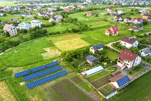 Vista aérea de una casa privada en verano con paneles solares fotovoltaicos azules en la azotea y en el patio
. - Foto, imagen