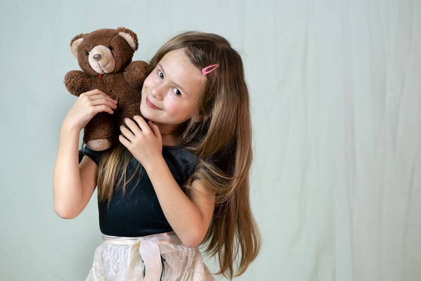 Гарненька дівчинка грає зі своєю плюшевою іграшкою ведмедя
. - Фото, зображення