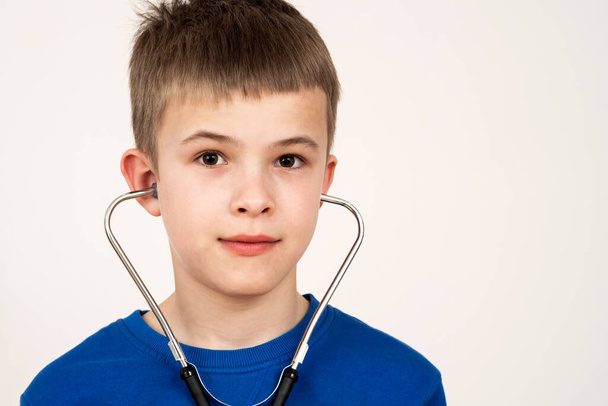Child boy playing doctor with stethoscope in ears. Pediatric, healthcare and people concept. - Фото, зображення