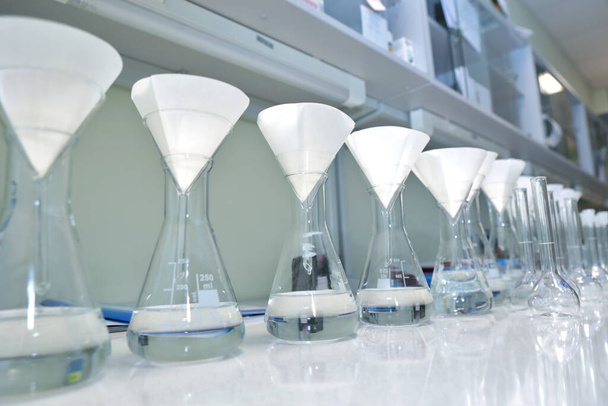 Kemiallisen kokeen suorittaminen laboratoriossa. Väripullot, joissa on kemiallisia reagensseja. Monet lasipullot ovat tiedemiehen käsissä. Kaunis värireagenssiliuos. Keltainen ja ruskea testi
 - Valokuva, kuva