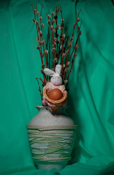 Coelho de brinquedo segura um ovo de galinha em uma cesta. Coelho de Páscoa com ovo
 - Foto, Imagem