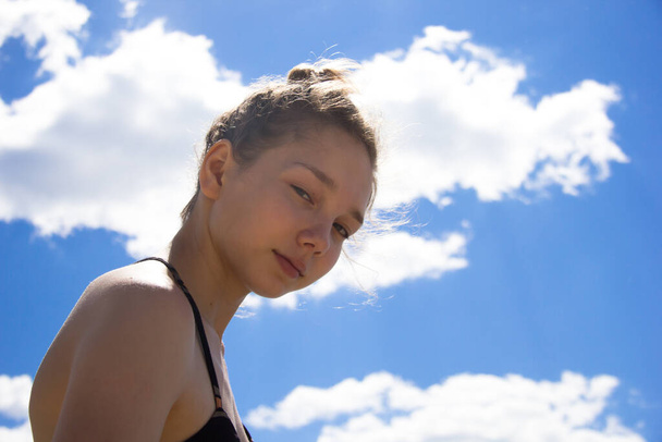 Portrait of young girl looking at camera on blue sky background in summertime - Fotografie, Obrázek