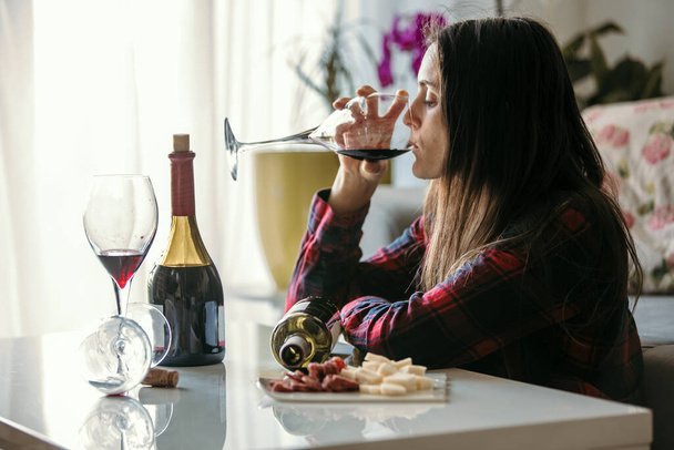 Sad tired woman, drinking wine at home, alone, sitting on the floor in living room, feeling depressed - Φωτογραφία, εικόνα