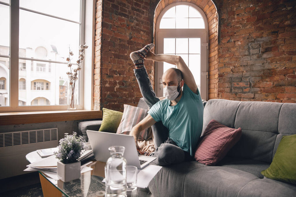 Young man doing yoga at home while being quarantine and freelance working - Фото, зображення