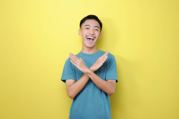 Feliz jovem asiático encantado com sinal de parada, isolado no fundo amarelo
  - Foto, Imagem