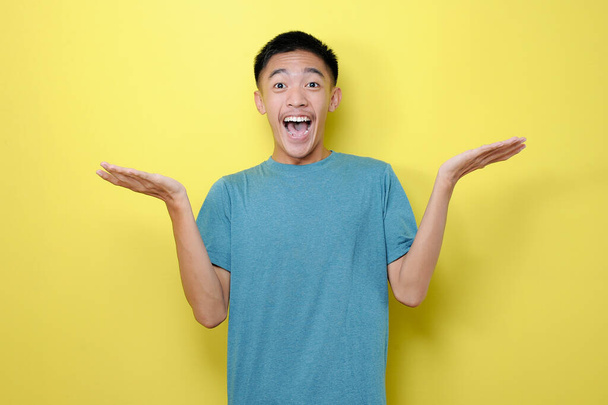 Retrato de sonrisa relajada joven asiático hombre obtener el mejor precio o mejor regalo, aislado sobre fondo amarillo
 - Foto, imagen