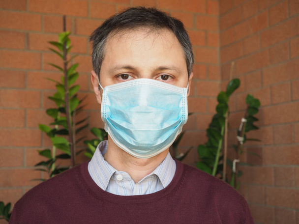 Mann mit Chirurgenmaske soll Covid-19-Infektion stoppen - Foto, Bild
