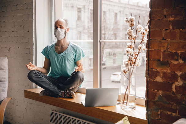 Young man doing yoga at home while being quarantine and freelance working - Φωτογραφία, εικόνα