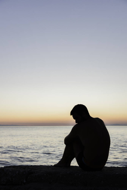 Gün batımında deniz kenarında bir adamın silueti.  - Fotoğraf, Görsel